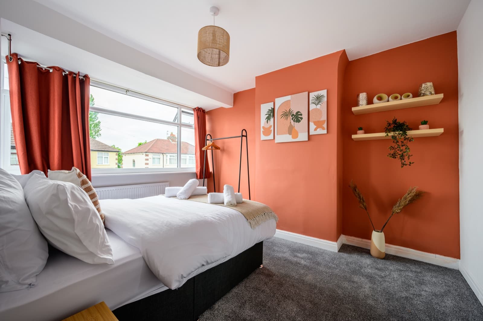 A double bedroom with a terracotta feature wall and a made-up bed