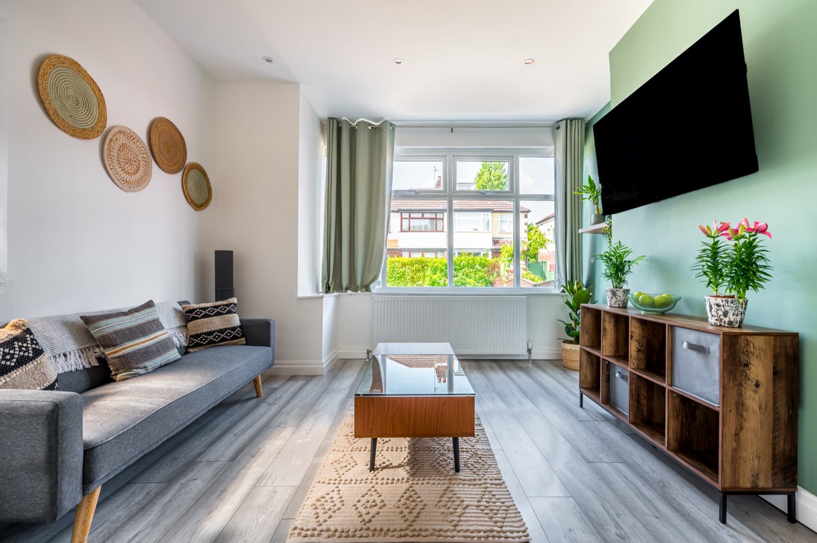 A finished living room with a grey corner sofa, plants and a bright window