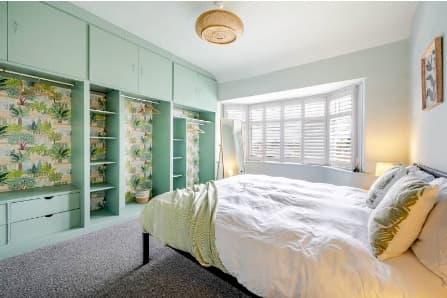 After: a finished bedroom in the same home two days later, made up with a warm terracotta feature wall