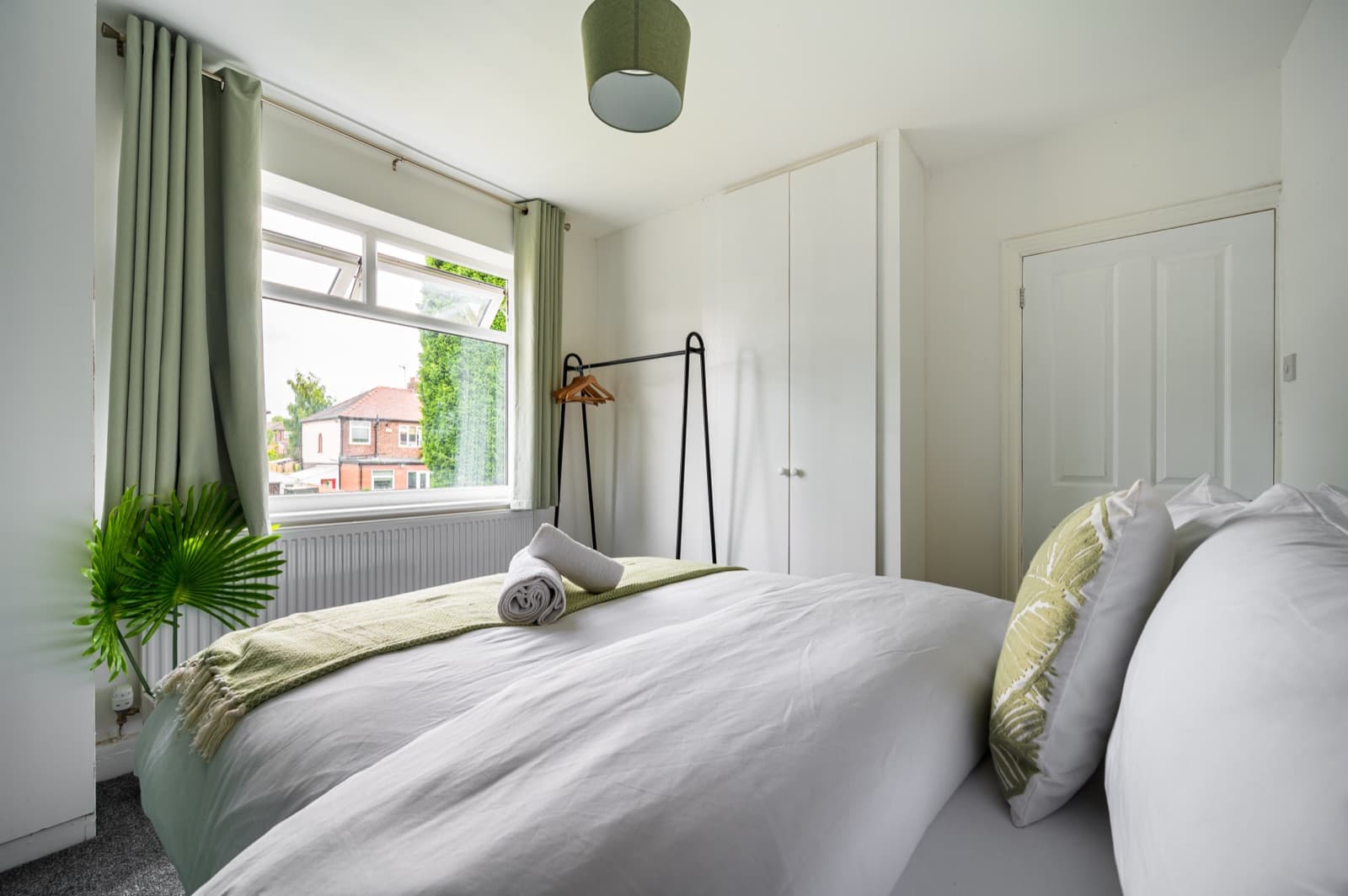 A calm bedroom with a freshly made bed beside a bright window